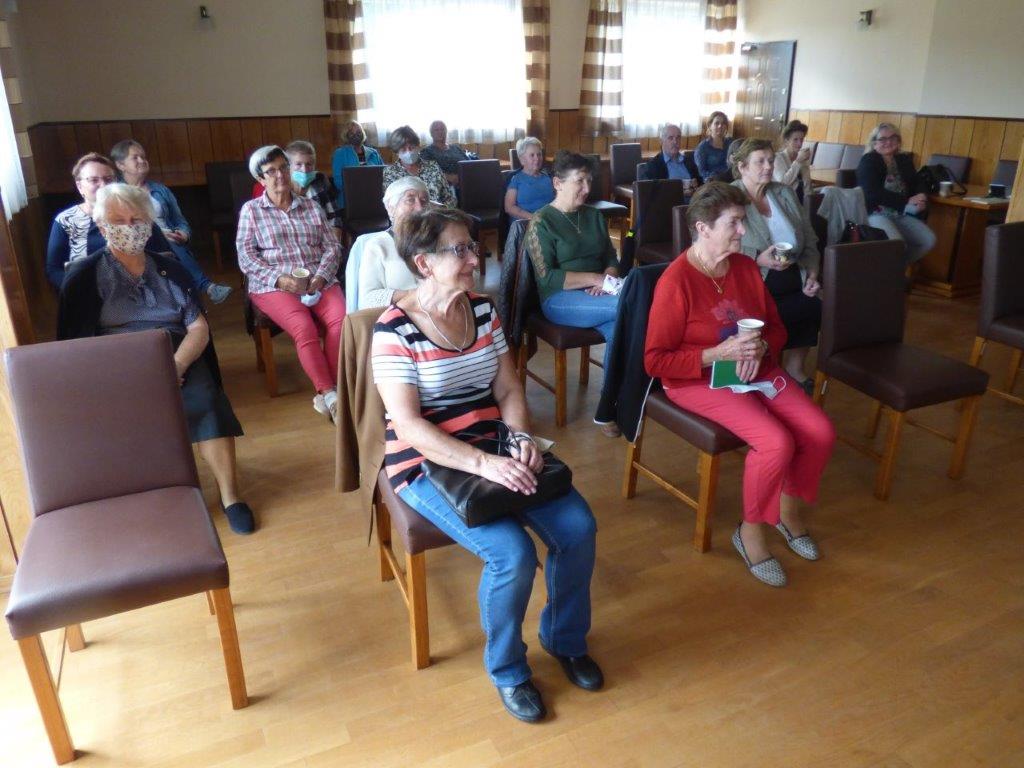 Seniorzy siedzą i słuchają wykładu