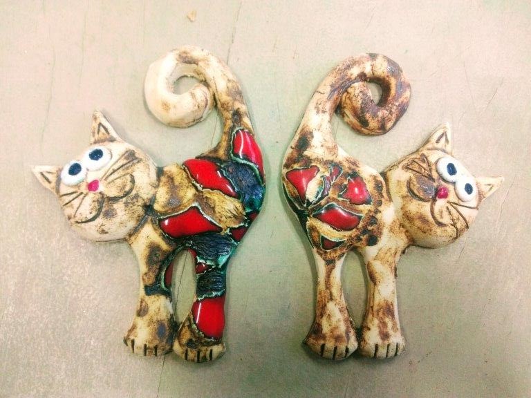 Na zdjęciu dwa ceramiczne kotki ozdobione czerwonym szkliwieniem.