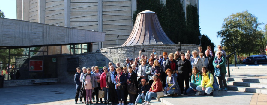 Uczestnicy wycieczki do Wrocławia stoją i siedzą na schodach przed budynkiem, w którym znajduje się Panorama Racławicka