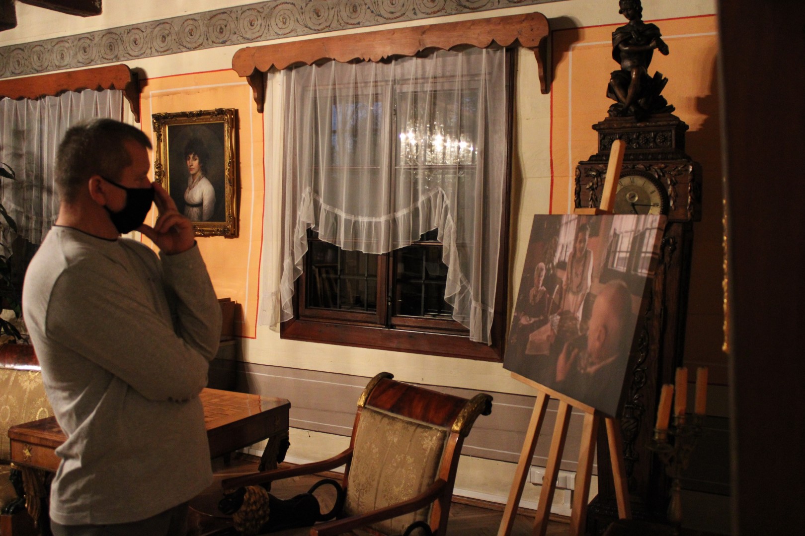 Uczestnik wernisażu stoi i w skupieniu przygląda się jednemu ze zdjęć, które tworzą wystawę fotograficzną.