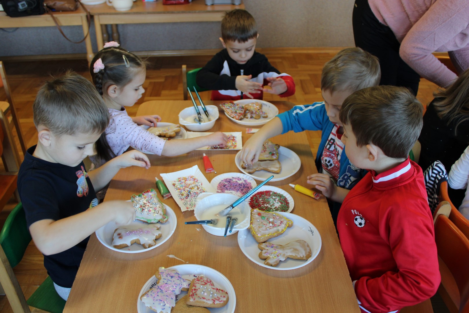 Pięcioro przedszkolaków ze Stronia siedzi przy stoliku i dekoruje pierniczki.