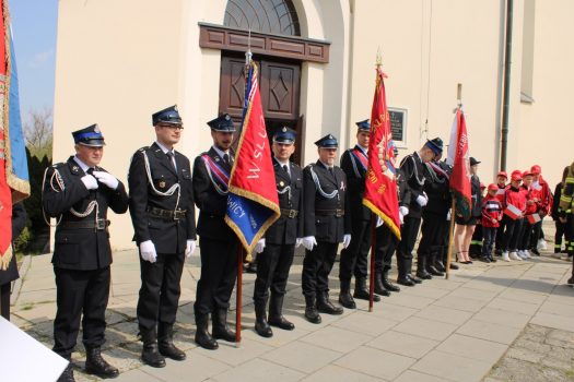Strażacy ubrani w odświętne mundury stoją w rzędzie obok kościoła w Stryszowie.