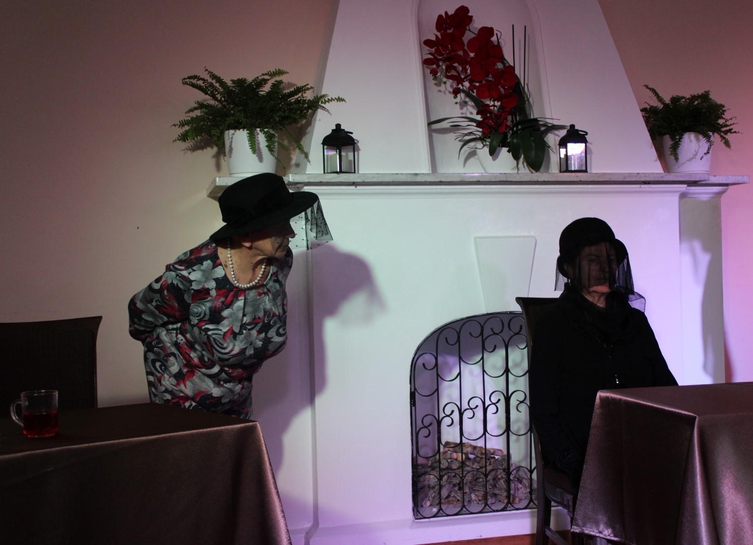 Dwie aktorki wcielające się w tytułowe wdowy ubrane są w ciemne stroje wraz z czarnymi kapeluszami z woalką, odgrywają tytułowe role w spektaklu „WDOWY” w Dworze Senator w Zakrzowie.
