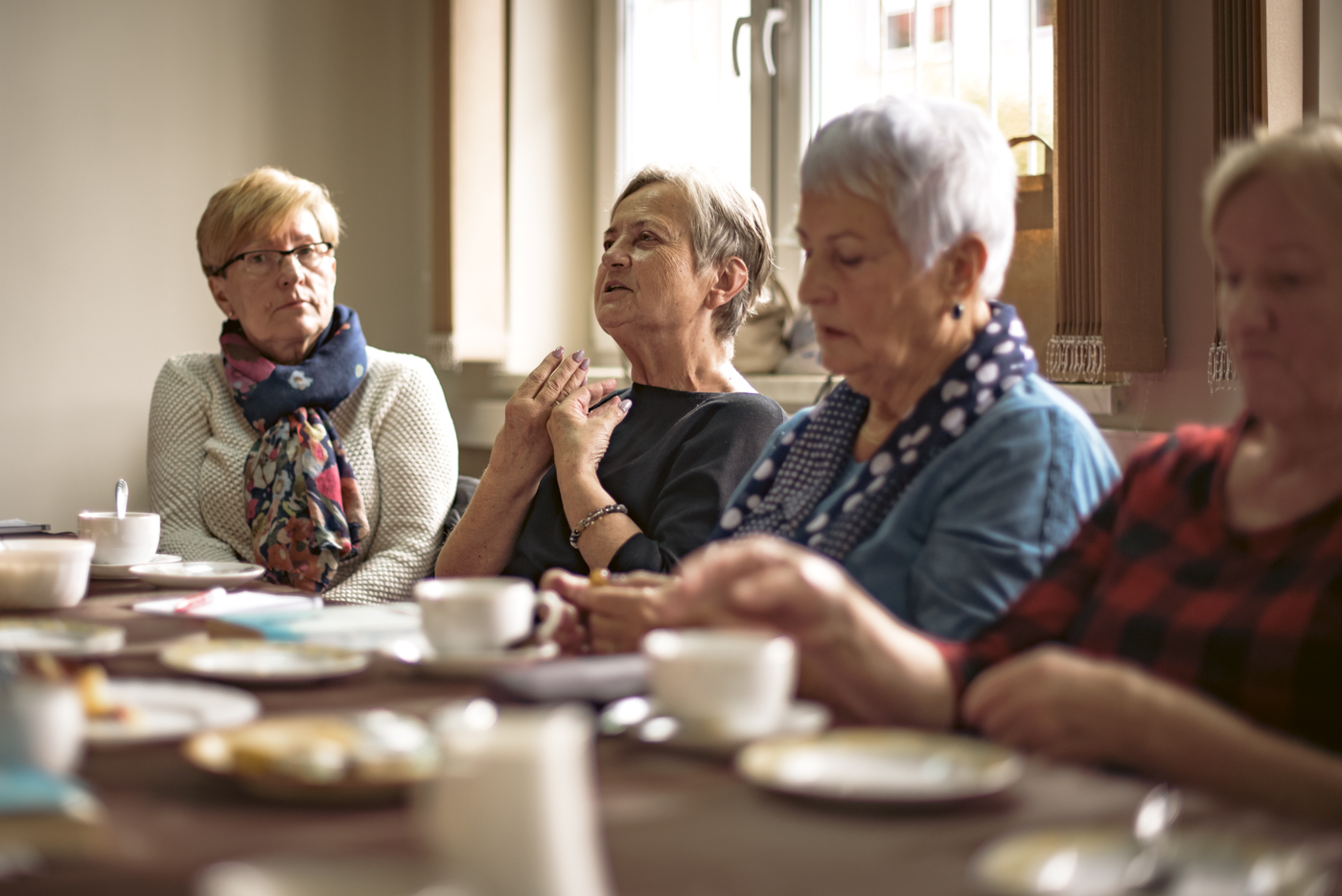 Na zdjęciu znajdują się cztery starsze kobiety, które siedzą przy stole w świetlicy Gminnego Ośrodka Kultury w Stryszowie, podczas spotkania Dyskusyjnego Klubu Książki. Jedna z nich wypowiada się na temat przeczytanej książki Massimo Gramelliniego „Niech ci się coś pięknego przyśni”.
