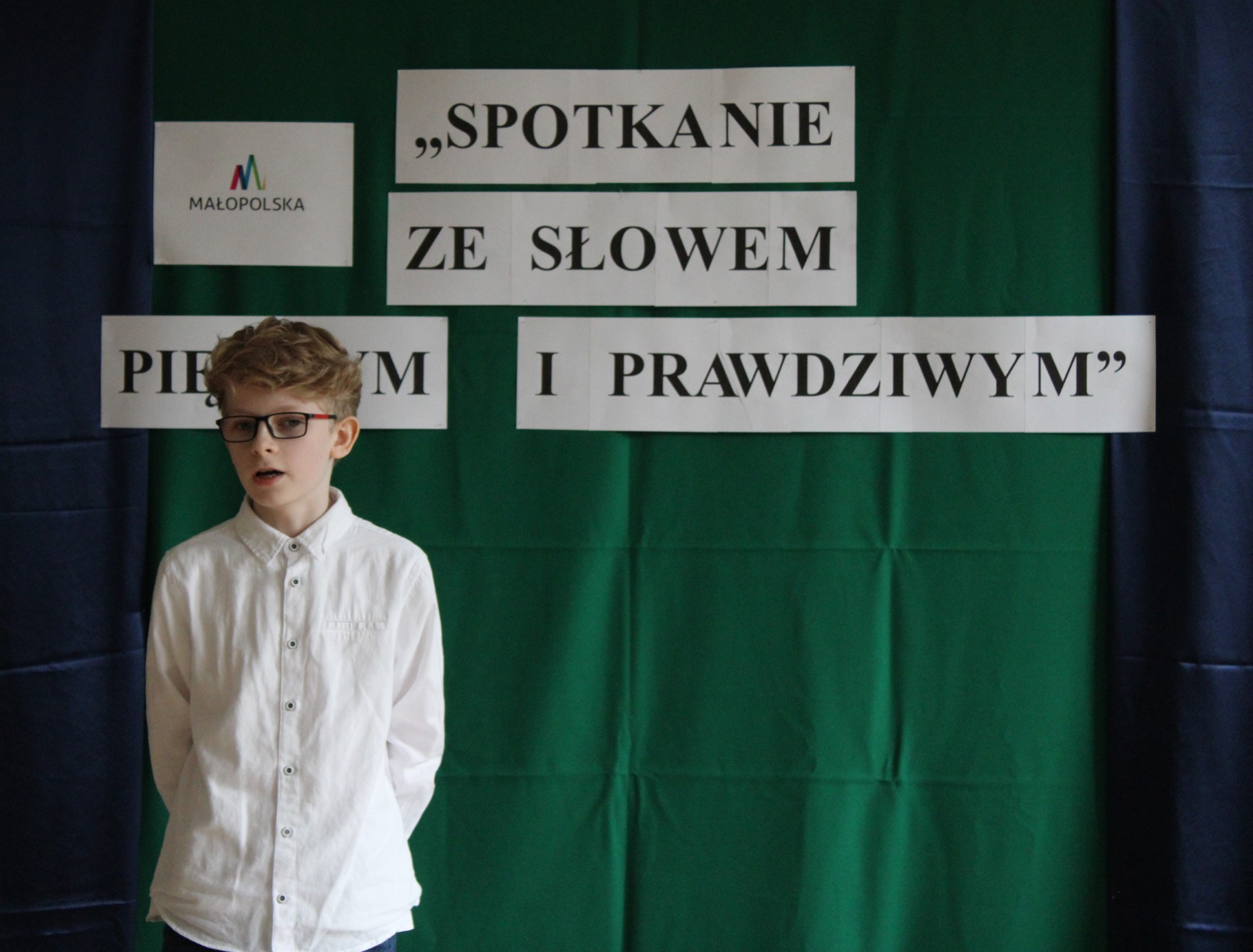 Na zdjęciu znajduje się chłopiec, który zajął pierwsze miejsce podczas Małopolskiego Konkursu Recytatorskiego – etapu gminnego „Spotkanie ze słowem pięknym i prawdziwym”, zorganizowanego na świetlicy Gminnego Ośrodka Kultury w Stroniu.